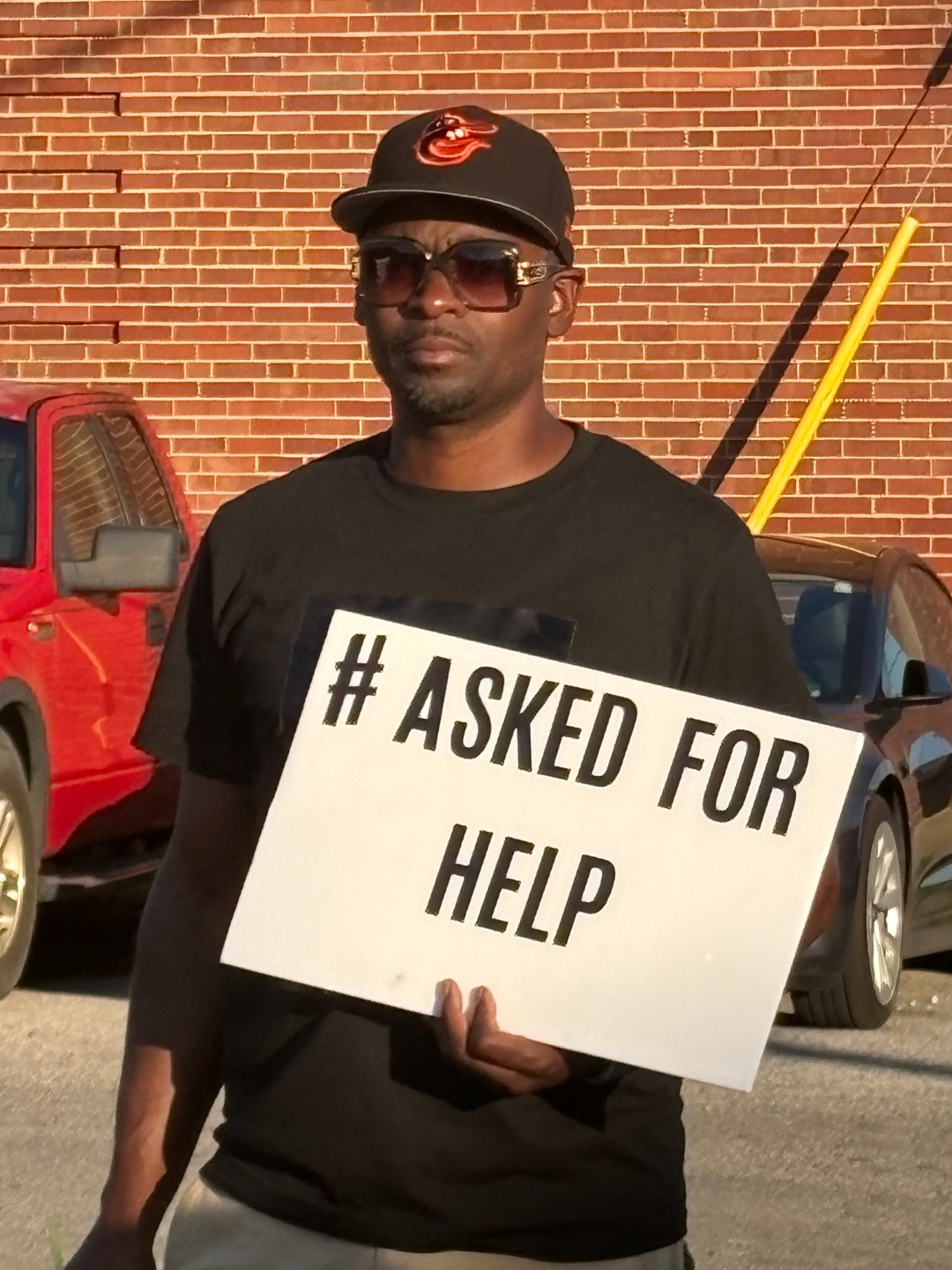 Man holding an AskedForHelp sign at the rally